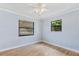 A bright bedroom with wood-look floors, two windows, and a ceiling fan at 1855 Pine Tree Dr, Edgewater, FL 32141