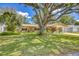 Charming home with a lush green lawn, mature trees, and beautifully landscaped front yard at 1855 Pine Tree Dr, Edgewater, FL 32141