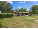 Wide shot of backyard showing the back of the house, a large lawn, and a chain link fence at 1905 Pine Tree Dr, Edgewater, FL 32141