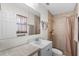 Tiled bathroom features a shower with peach-colored shower curtain, as well as a white sink and toilet at 1905 Pine Tree Dr, Edgewater, FL 32141