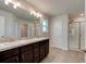 Bathroom featuring double sinks, a large mirror, and a walk-in shower at 208 Lagoon Mist Ct, Oak Hill, FL 32759