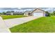 Long driveway and manicured lawn leading to a brick home with a white garage door at 208 Lagoon Mist Ct, Oak Hill, FL 32759