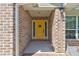 Charming yellow front door framed by brick and sidelights creates a welcoming entryway at 208 Lagoon Mist Ct, Oak Hill, FL 32759