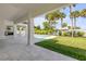 A covered patio overlooks the backyard, featuring a pool, built in grill and lush lawn at 212 Due East St, New Smyrna Beach, FL 32169