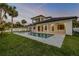 Expansive backyard with a sparkling pool, lush green lawn, and covered patio creates a serene outdoor retreat at 212 Due East St, New Smyrna Beach, FL 32169