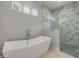Modern bathroom featuring a freestanding tub, marble shower, glass door, and clerestory windows at 212 Due East St, New Smyrna Beach, FL 32169