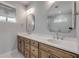 Bathroom with double sinks, decorative mirrors, wood cabinets, light colored countertop, and window at 212 Due East St, New Smyrna Beach, FL 32169
