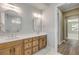 Bathroom vanity with double sinks, decorative mirrors, wood cabinets, light colored countertop, and tile floor at 212 Due East St, New Smyrna Beach, FL 32169