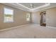 Bright bedroom features neutral carpet, tray ceiling with fan, natural light, and en-suite bathroom with hardwood floor at 212 Due East St, New Smyrna Beach, FL 32169
