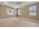 Spacious bedroom with neutral carpet, tray ceiling with fan, and plenty of natural light from multiple windows at 212 Due East St, New Smyrna Beach, FL 32169