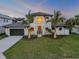 Beautiful exterior elevation with a large garage, front lawn, and palm trees at 212 Due East St, New Smyrna Beach, FL 32169
