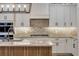 Beautiful kitchen with a stone countertop island, white cabinets, and a stone backsplash with stainless steel appliances at 212 Due East St, New Smyrna Beach, FL 32169
