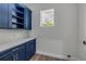 Well-lit laundry room features blue cabinets, white countertop, wood floor, and a bright window at 212 Due East St, New Smyrna Beach, FL 32169