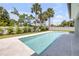 Inviting rectangular pool surrounded by lush landscaping, a bright white fence, and elegant light-colored stone tiling at 212 Due East St, New Smyrna Beach, FL 32169