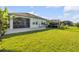 Spacious backyard with lush green grass, screened-in lanai, trampoline, and fenced yard at 220 Venetian Palms Blvd, New Smyrna Beach, FL 32168