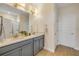Bathroom with double sinks, gray cabinets, granite countertops, and stylish bronze fixtures at 220 Venetian Palms Blvd, New Smyrna Beach, FL 32168