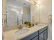 Bathroom featuring double sinks with granite countertops, framed mirror, and white cabinets at 220 Venetian Palms Blvd, New Smyrna Beach, FL 32168