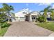Beautiful two-story home with a brick driveway, palm trees, and a two-car garage at 220 Venetian Palms Blvd, New Smyrna Beach, FL 32168