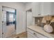 Hallway with white cabinets, quartz counters, mosaic tile backsplash and wood look floors at 220 Venetian Palms Blvd, New Smyrna Beach, FL 32168