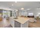 Open-concept kitchen with stainless steel appliances and a central island, leading to a sunlit dining and living area at 220 Venetian Palms Blvd, New Smyrna Beach, FL 32168