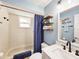 Bright bathroom featuring a tub with shower, floating shelves, and blue accents at 2236 Davis Dr, New Smyrna Beach, FL 32168