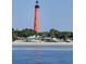View of a bright red lighthouse next to beachside shops and blue ocean at 2236 Davis Dr, New Smyrna Beach, FL 32168