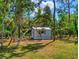 Exterior view of a cozy storage shed with a matching roof, nestled among lush trees at 2656 Old Smyrna Trl, New Smyrna Beach, FL 32168