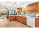 Bright kitchen with wood cabinets, wood look floors, white appliances, and view of screened lanai at 3016 Mango Tree Dr, Edgewater, FL 32141