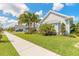 Well-manicured front yard with lush green grass, palm trees, and charming home exterior, a perfect welcome at 3219 Modena Way, New Smyrna Beach, FL 32168