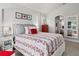 A well-lit bedroom with a bed that has a floral pattern and a full-length mirror reflecting the room at 3349 Glenshane Way, Ormond Beach, FL 32174