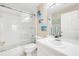 Bright bathroom with a white vanity, toilet, shower-tub combo, and beach-themed wall art at 402 Bouchelle Dr # 206, New Smyrna Beach, FL 32169