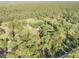 Wide aerial perspective of a property featuring a home, outbuildings, a pond, and surrounding forest at 416 Western Rd, New Smyrna Beach, FL 32168