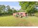 Red outbuilding with a green John Deere tractor parked outside on the lawn at 416 Western Rd, New Smyrna Beach, FL 32168