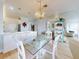 Open dining area featuring a glass table, white chairs, and an elegant chandelier near the kitchen at 438 Bouchelle Dr # 104, New Smyrna Beach, FL 32169