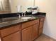 Bathroom vanity with dark granite countertop, undermount sink, and wooden cabinetry at 468 Bouchelle Dr # 128, New Smyrna Beach, FL 32169