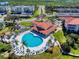 A beautiful aerial view of a clubhouse and a heart shaped community pool surrounded by manicured landscaping at 468 Bouchelle Dr # 128, New Smyrna Beach, FL 32169