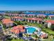 Scenic aerial shot of condo buildings featuring red tile roofs, lush landscaping, community pool, and waterfront views at 468 Bouchelle Dr # 128, New Smyrna Beach, FL 32169