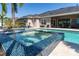 In-ground pool and spa feature beautiful tile, with the outdoor dining area nearby at 481 Sweet Bay Ave, New Smyrna Beach, FL 32168