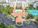 Drone shot shows resort-style community pool, clubhouse, parking, and two blue tennis courts at 5300 S Atlantic Ave # 16-205, New Smyrna Beach, FL 32169