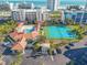 Birds-eye shot of sparkling clover-shaped pool, tennis courts, clubhouse, and manicured grounds at 5300 S Atlantic Ave # 16-205, New Smyrna Beach, FL 32169