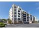 Modern condo building showcasing spacious balconies with blue railings, lush landscaping, and ample parking at 5300 S Atlantic Ave # 20-507, New Smyrna Beach, FL 32169