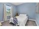 Cozy bedroom features a comfortable bed, light blue walls and natural light from the window at 5607 Estero Loop, Port Orange, FL 32128