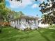 Charming white home with a well-manicured lawn, mature trees, and a serene neighborhood setting, creating a picturesque curb appeal at 600 Magnolia St, New Smyrna Beach, FL 32168