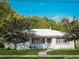 Charming white brick home with a bright green door, lush lawn, and beautiful mature trees at 600 Magnolia St, New Smyrna Beach, FL 32168