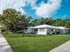 Charming traditional white brick home with a green lawn and mature trees under a blue sky at 600 Magnolia St, New Smyrna Beach, FL 32168