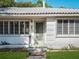 Close-up of a charming white home's entrance with a decorative light green door, well-kept lawn, and tidy landscaping at 600 Magnolia St, New Smyrna Beach, FL 32168