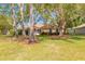 Wide shot of the green backyard featuring mature shade trees and a screened-in patio at 6093 Sabal Creek Blvd, Port Orange, FL 32128