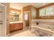 A well-lit bathroom with double vanity sinks, a tub, a shower, and tan walls at 6093 Sabal Creek Blvd, Port Orange, FL 32128