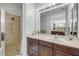 Well-lit bathroom featuring a glass-enclosed shower, dark wood cabinets and a large mirror reflecting double vanity at 634 Woodford Dr, Debary, FL 32713