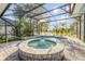 A screened-in pool and hot tub are surrounded by brick pavers with lake views beyond at 634 Woodford Dr, Debary, FL 32713
